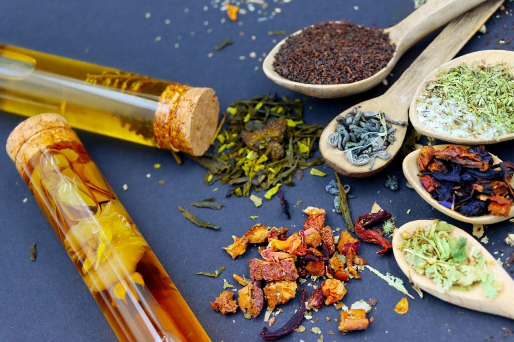 Colorful assortment of loose leaf teas and spices displayed on wooden spoons with test tubes.